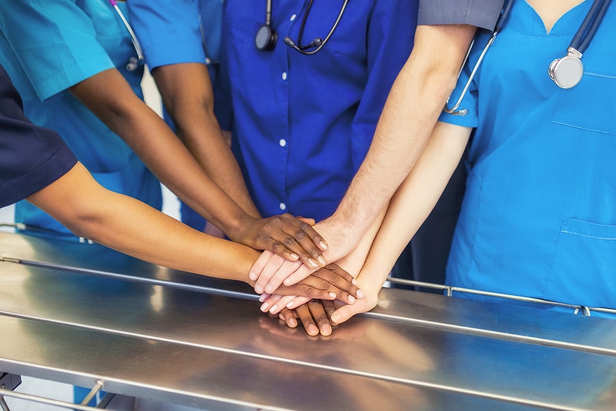 Group of healthcare providers with their hands in the middle